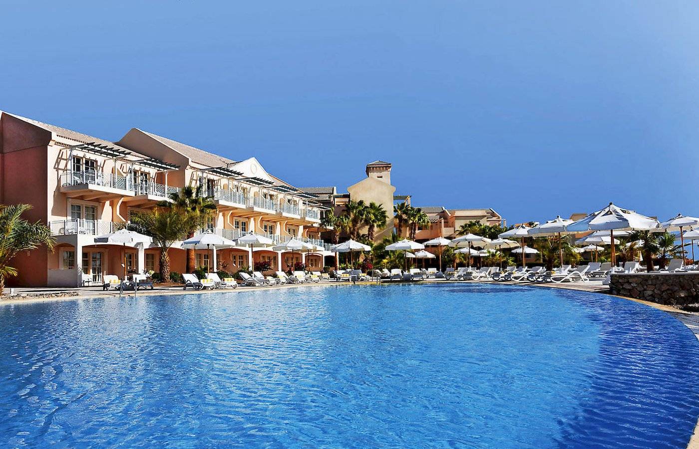 Poolbereich im Moevenpick Resort & Spa El Gouna mit vielen Sonnenliegen und umliegenden Hotels