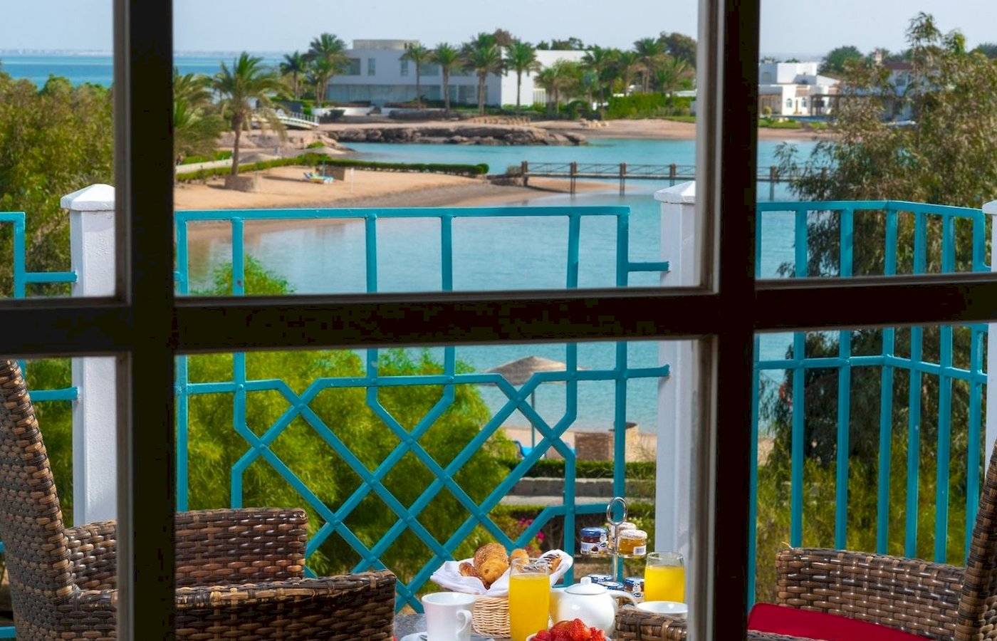 Frühstück auf dem Balkon im Mövenpick Resort & Spa El Gouna mit Blick auf den Ozean und eine tropische Landschaft.