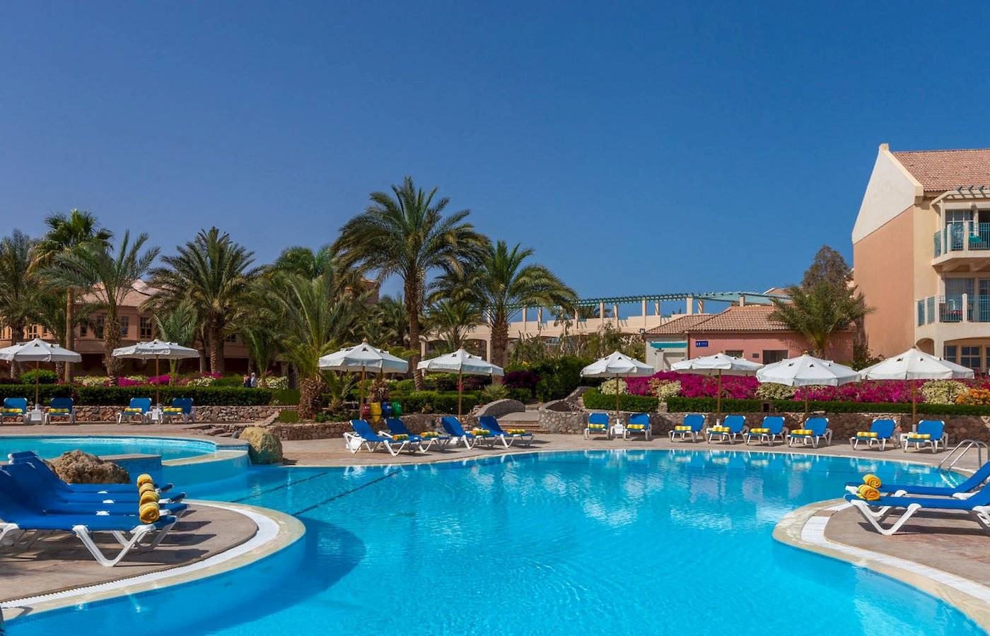 Außenpool des Mövenpick Resort & Spa El Gouna mit Loungeliegen und Sonnenschirmen.