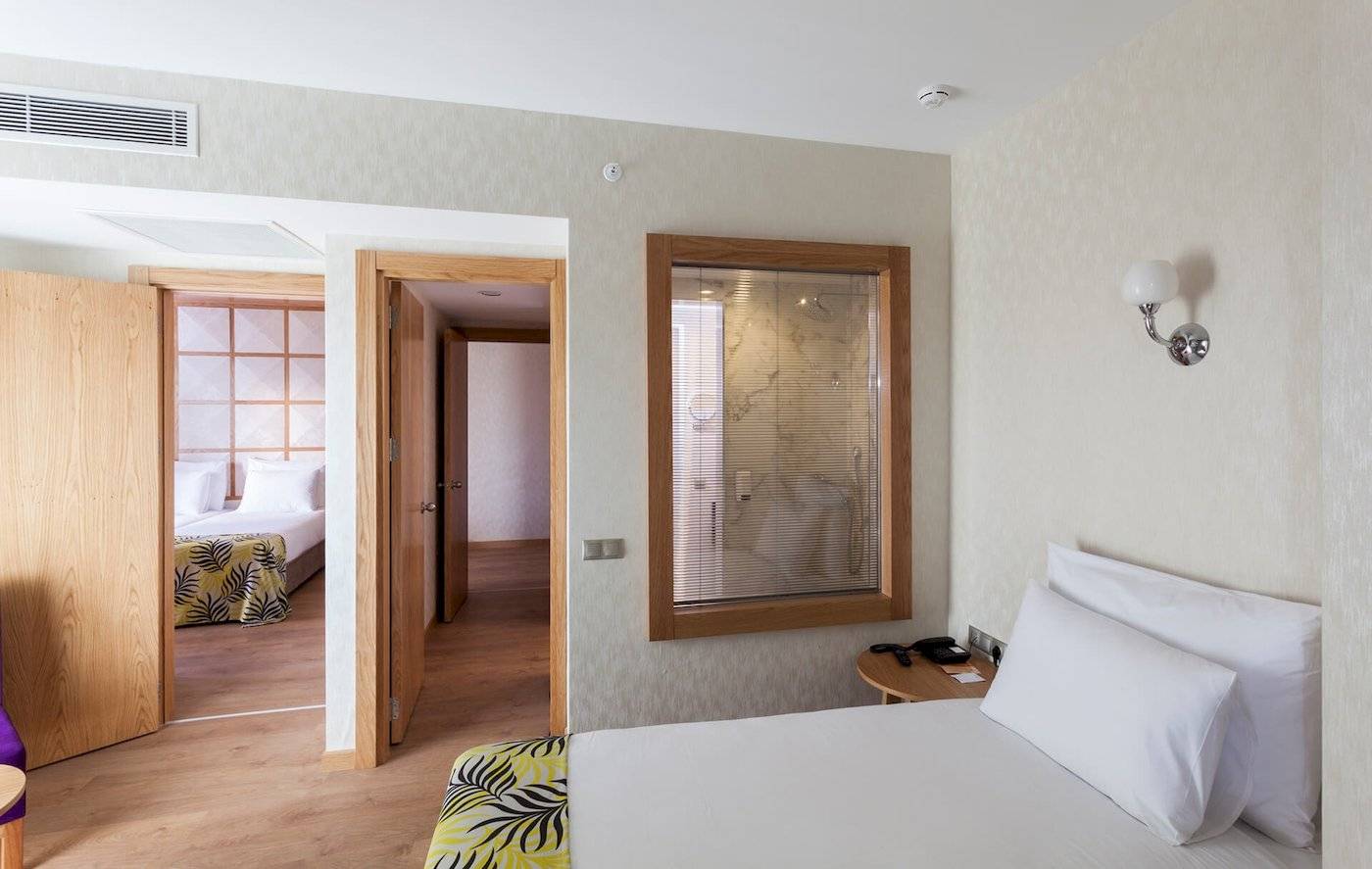 Innenansicht eines Zimmers im Defne Defnem Hotel mit Bett, Nachttisch und Badezimmer mit Dusche