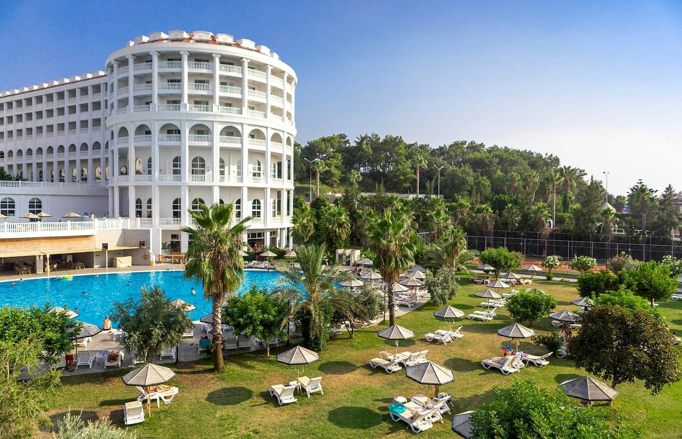 Defne Defnem Hotel Außenbereich mit Swimmingpool, Liegestühlen und Palmen.