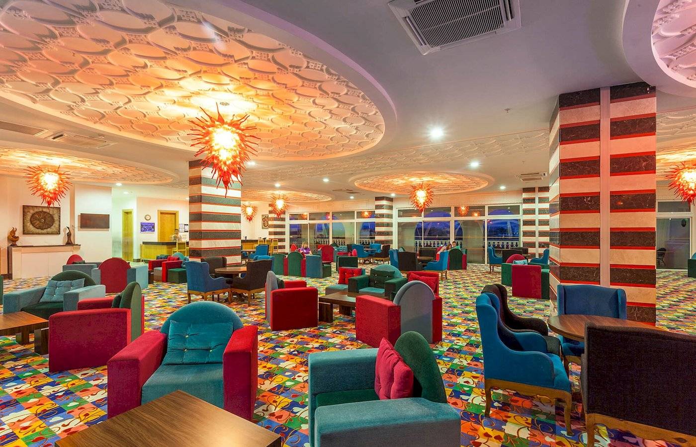 Lobby des Defne Defnem Hotels mit bunten Stühlen und Tischen.
