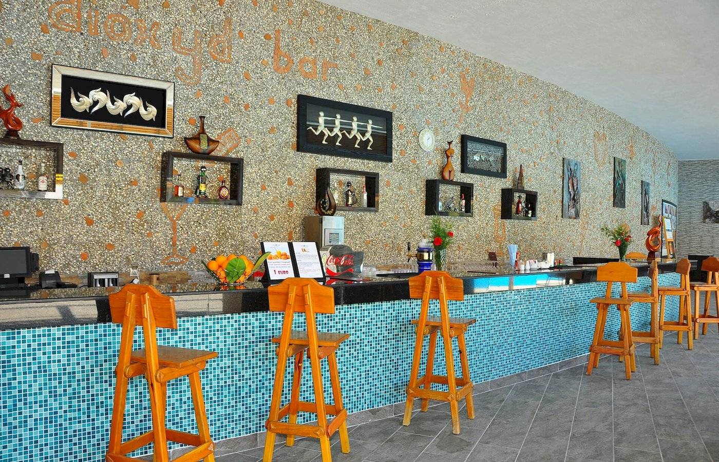 Innenansicht der Bar im Defne Defnem Hotel mit Holzstühlen, blauen Fliesen und Wanddekorationen.