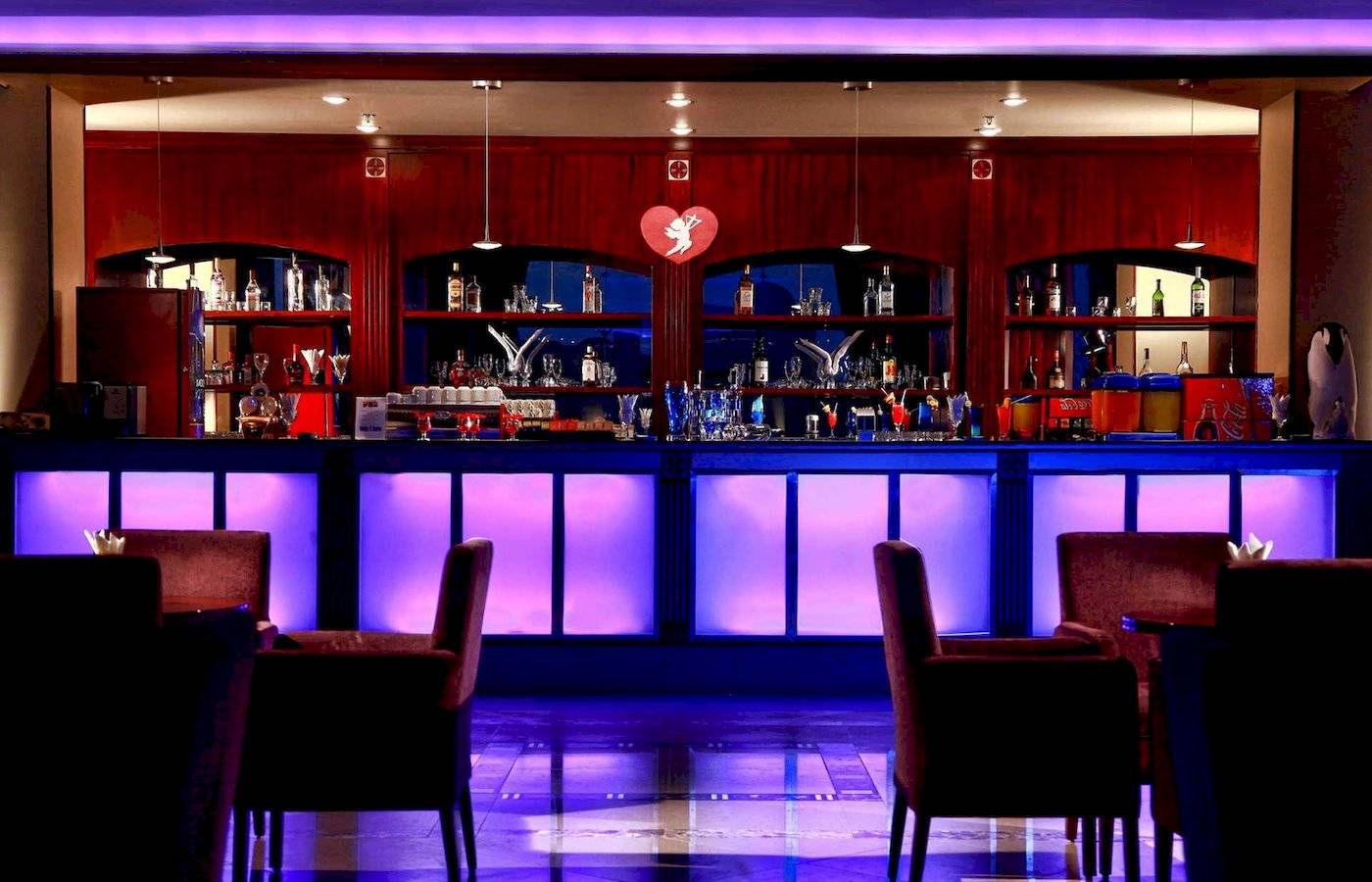 Innenansicht der Cocktailbar im Stella Gardens Resort & Spa Makadi Bay mit lila Beleuchtung und roten Stühlen