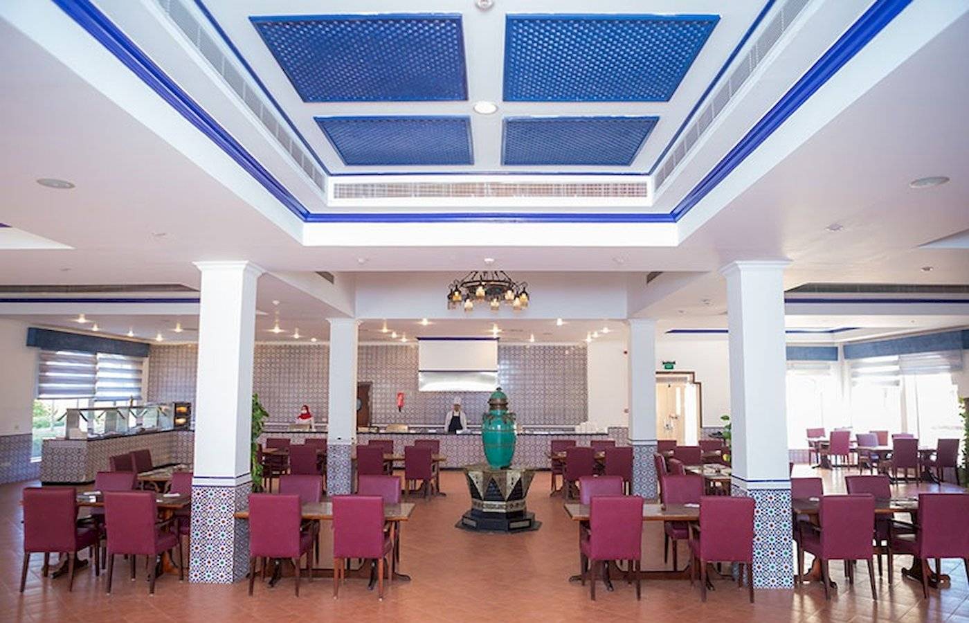 Innenbereich des Stella Gardens Resort & Spa Makadi Bay, mit Tisch und Stühlen, und einer grünen Vase in der Mitte.