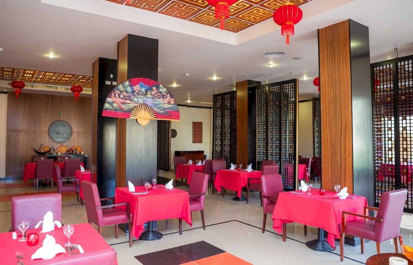 Restaurant im Stella Gardens Resort & Spa Makadi Bay mit roten Tischen und Stühlen.