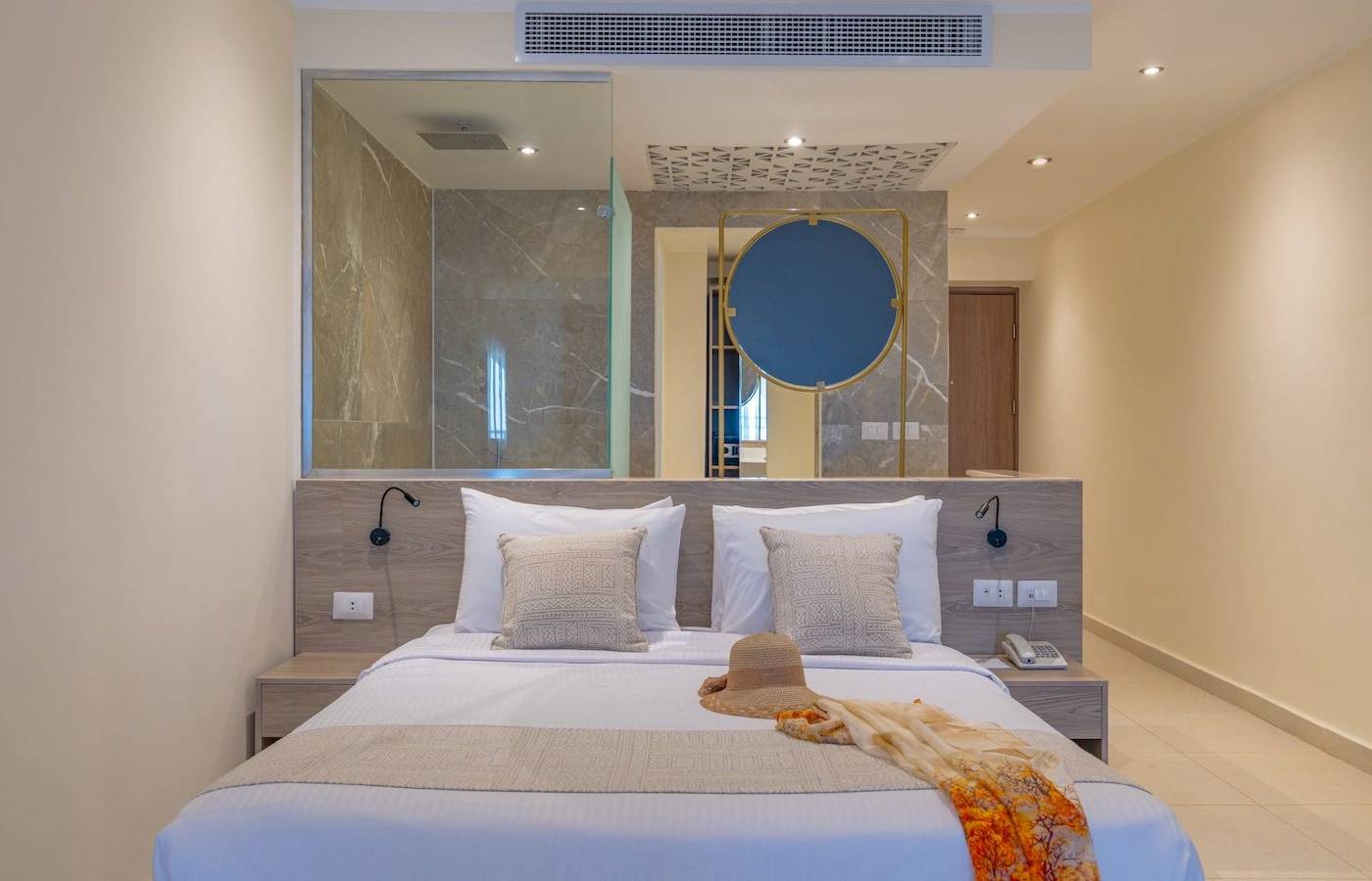 Hotelzimmer im Three Corners Equinox Beach Resort mit einem Bett, Kissen, Hut und Decken.