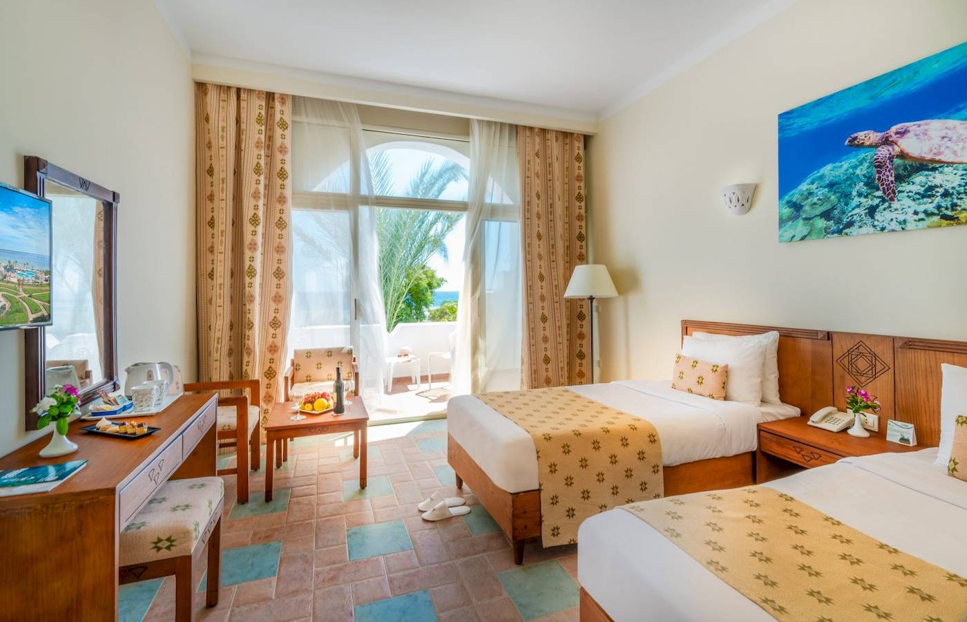 Zimmer im Three Corners Equinox Beach Resort mit zwei Betten, Tisch, Stuhl, Balkon und Meerblick