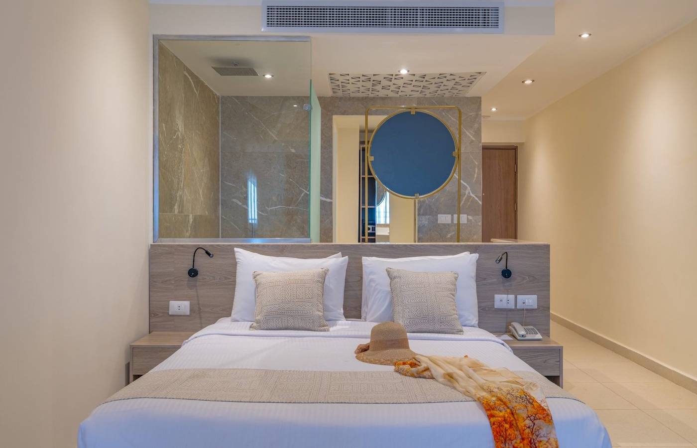 Schlafzimmer im Three Corners Equinox Beach Resort mit einem Bett, Kissen, einem Hut und einer Decke.