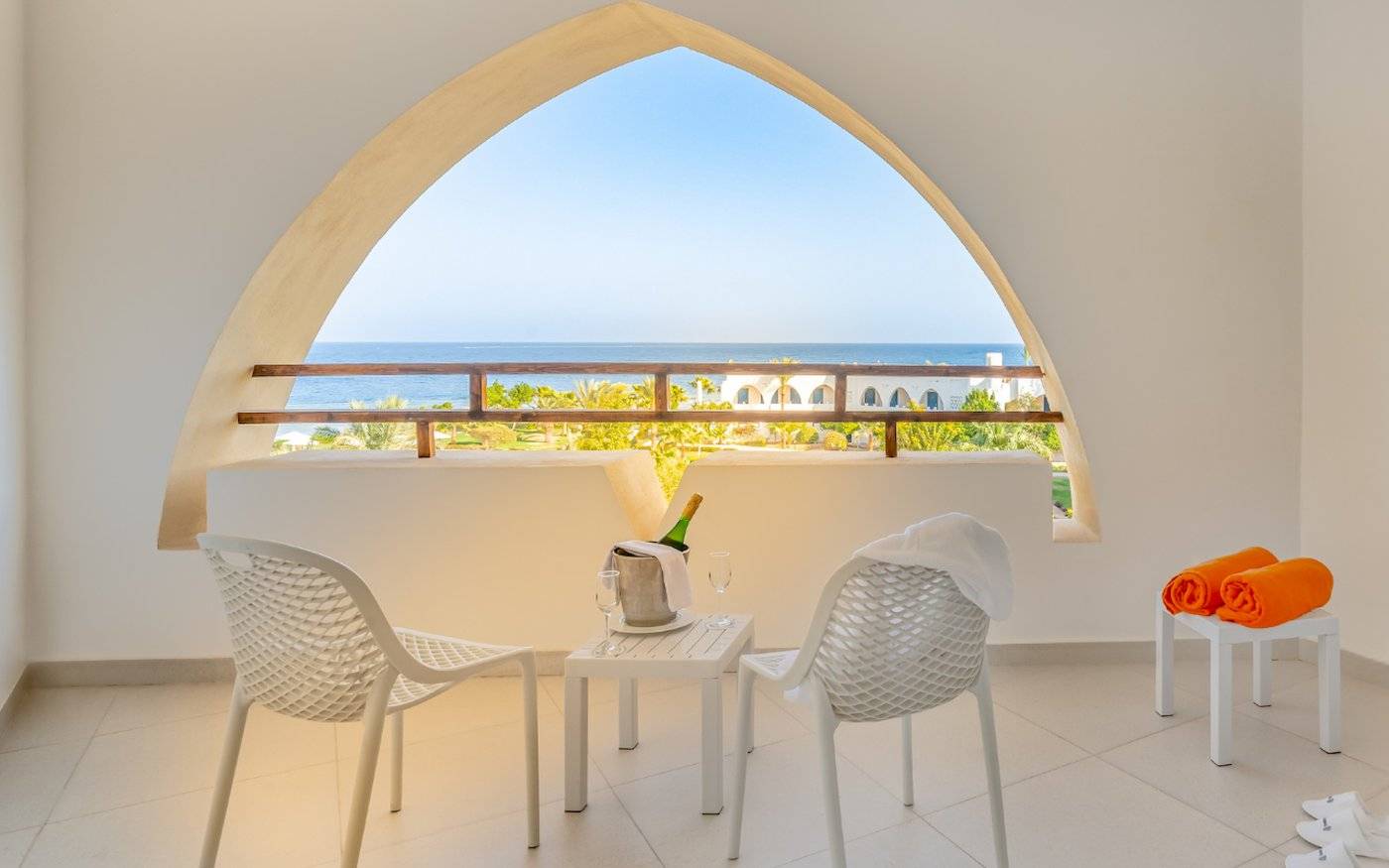 Balkon des Three Corners Equinox Beach Resort mit Blick auf das Meer und weiße Möbel.