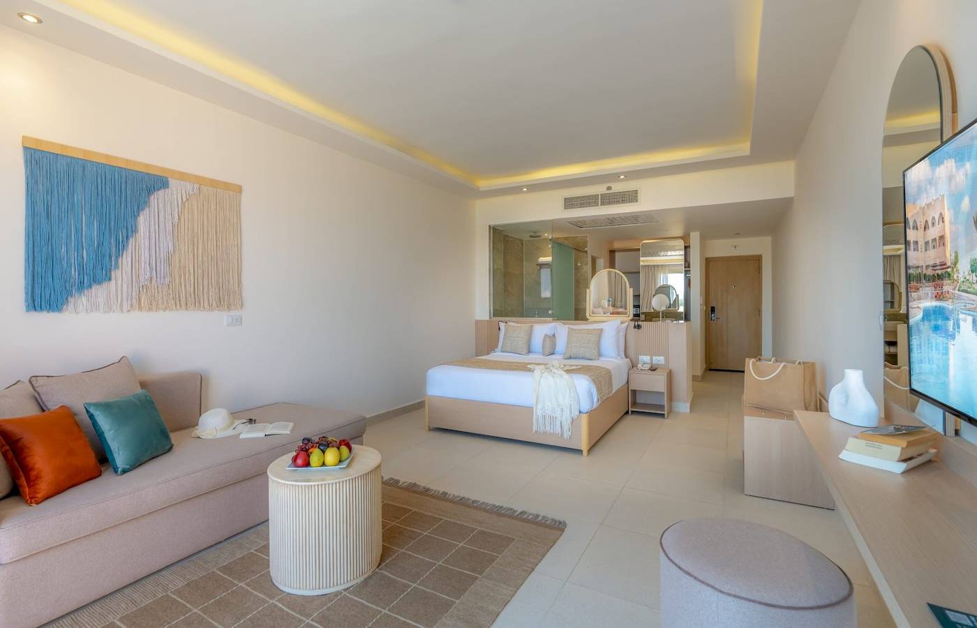 Suite-Interieur im Three Corners Equinox Beach Resort mit Bett, Sofa, Tisch und Fernseher.