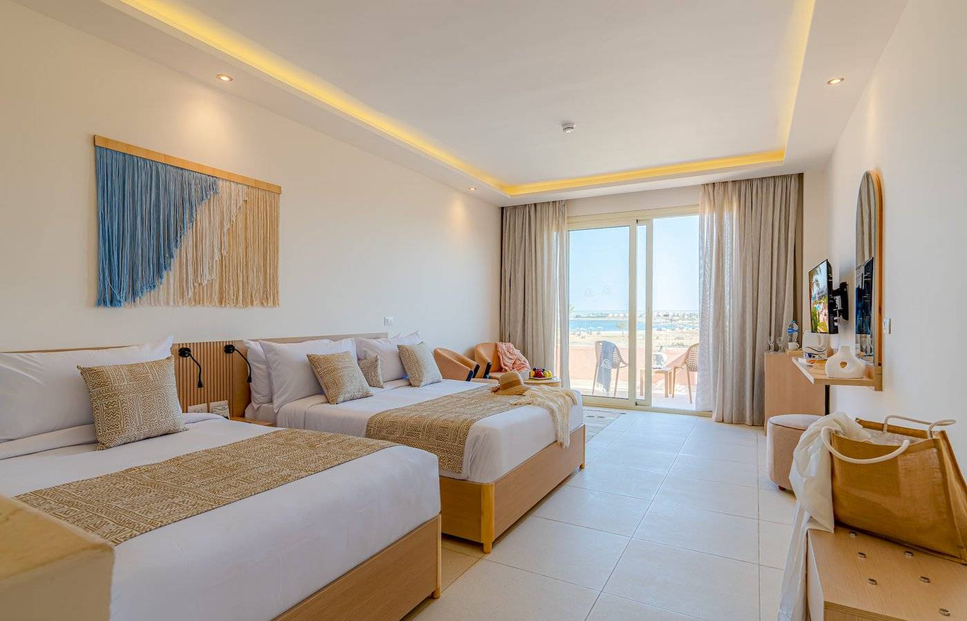 Zwei Betten in einem Hotelzimmer im Three Corners Equinox Beach Resort mit Blick auf das Meer.