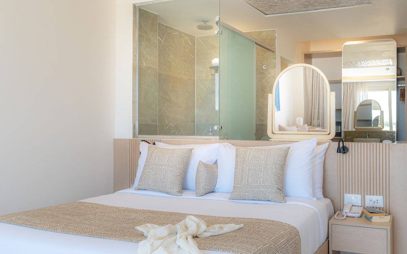 Schlafzimmer im Three Corners Equinox Beach Resort mit großem Bett, Dekor und Badezimmerspiegel