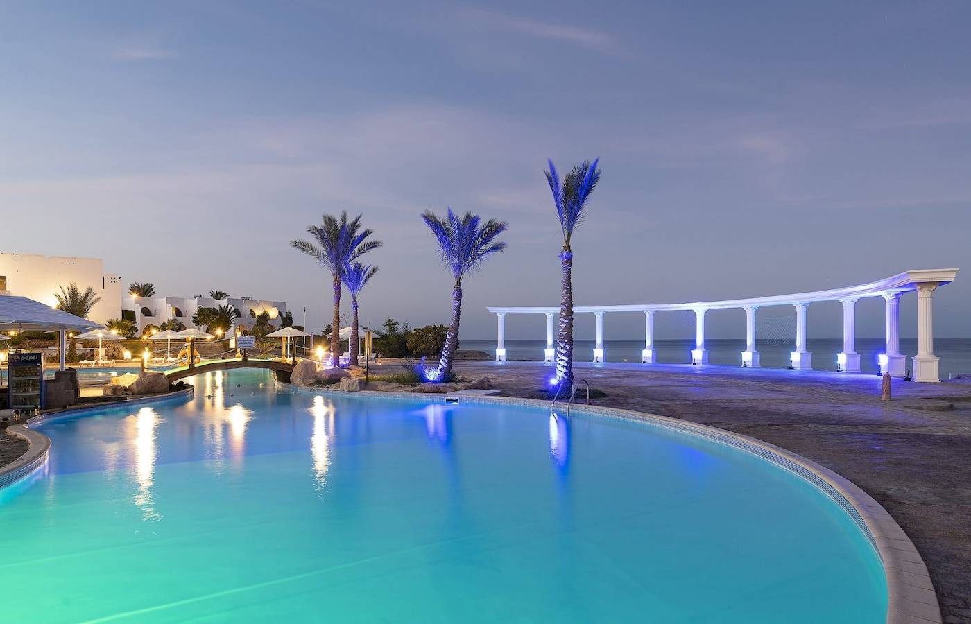 Ein Pool im Three Corners Equinox Beach Resort bei Nacht, beleuchtet von blauen Lichtern.