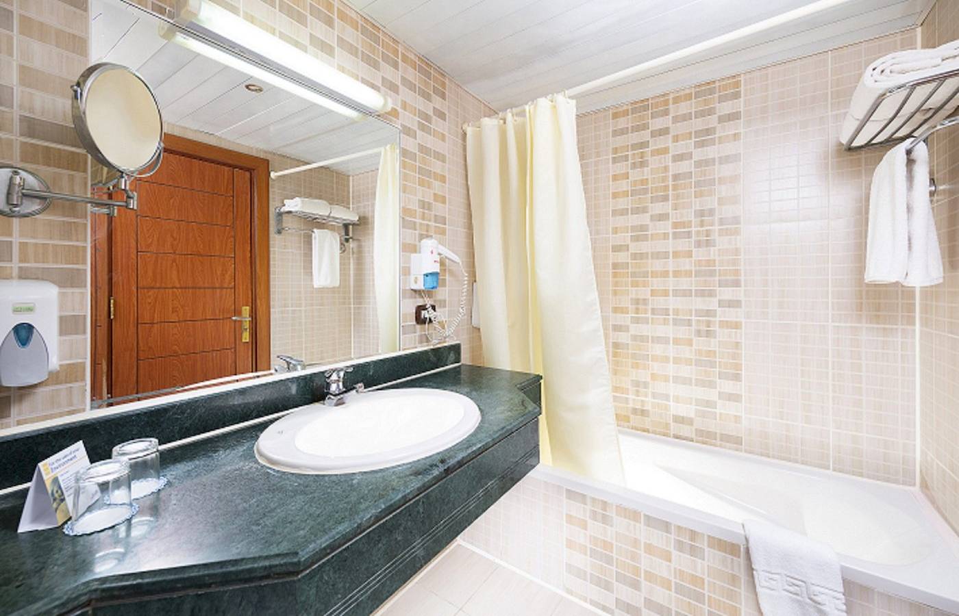 Badezimmer im Three Corners Equinox Beach Resort Hotel mit Waschbecken, Spiegel und Badewanne.
