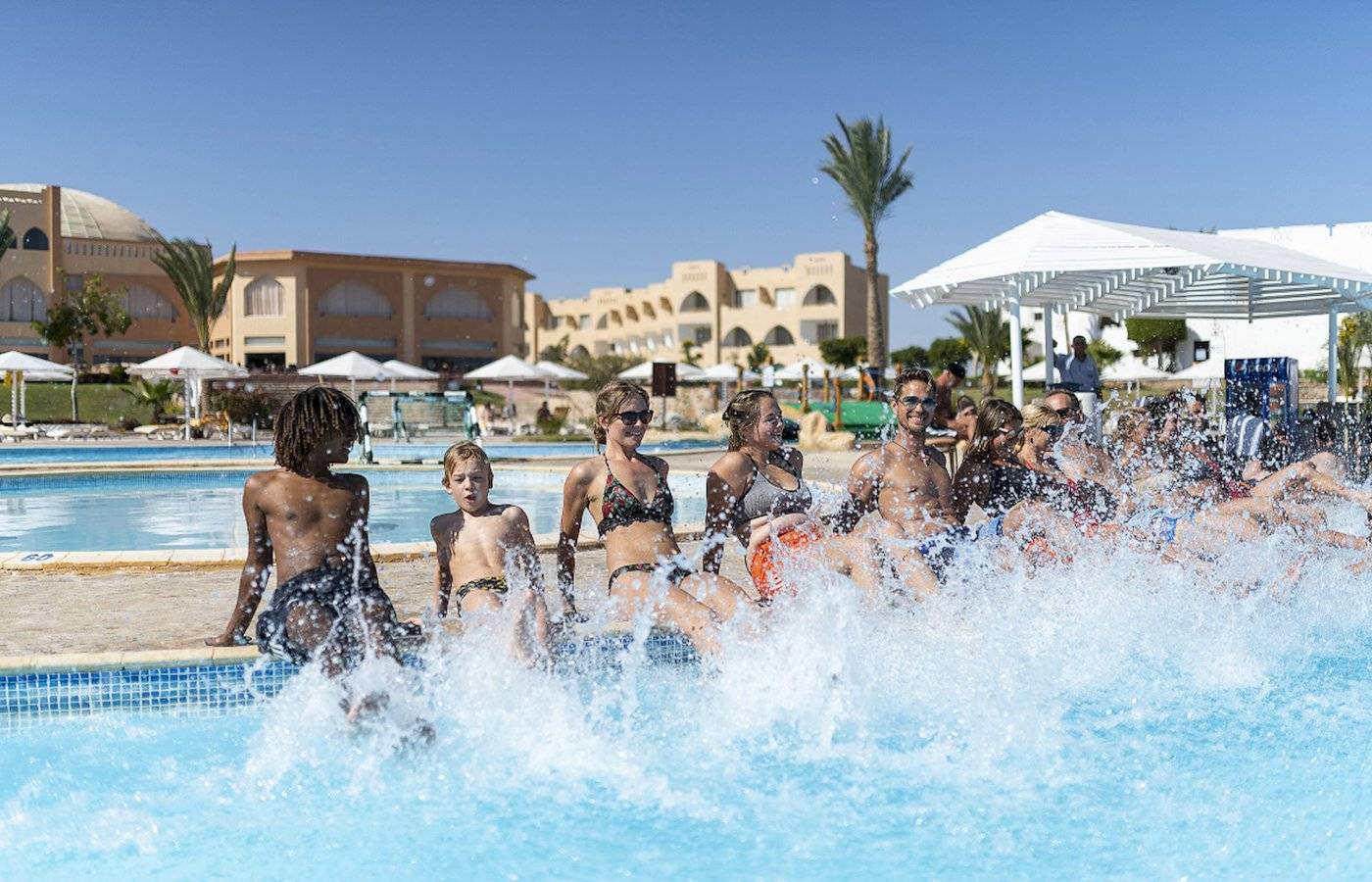 Gruppe von Kindern und Erwachsenen, die Spaß im Schwimmbecken des Three Corners Equinox Beach Resorts haben.