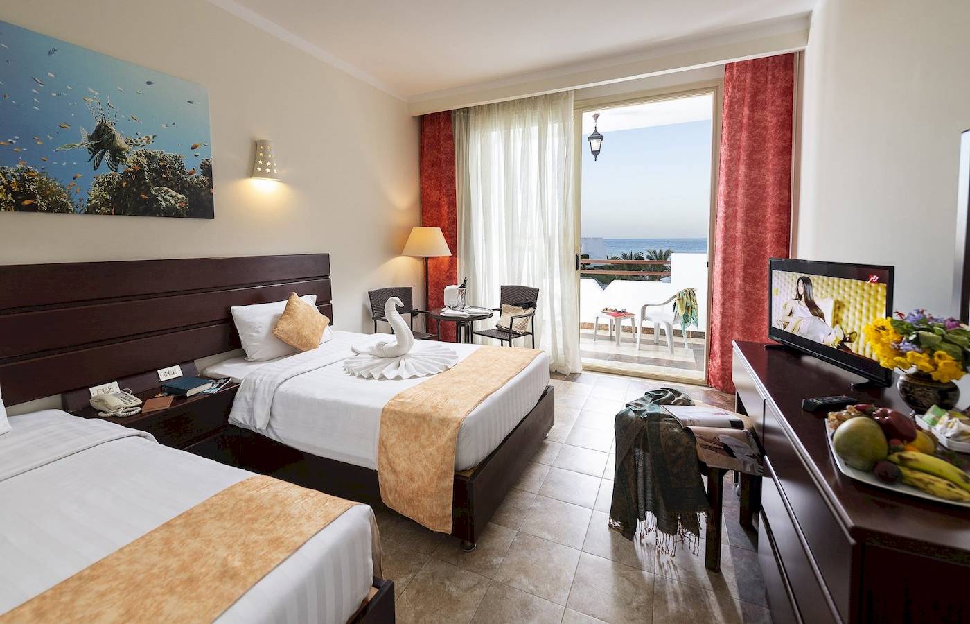 Doppelzimmer im Three Corners Equinox Beach Resort mit Meerblick, zwei Betten, Fernseher, und Balkon.