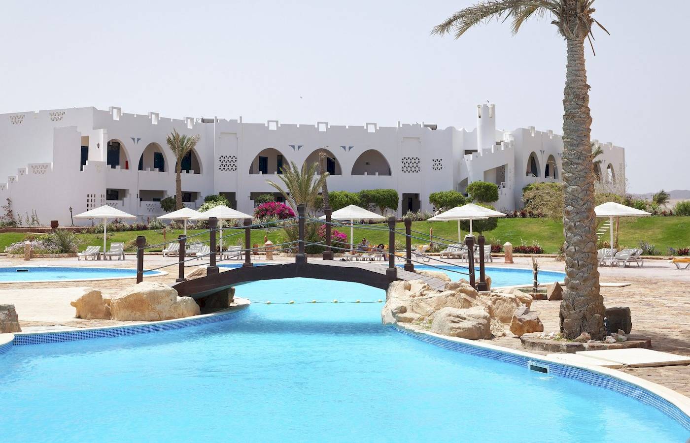 Außenpool im Three Corners Equinox Beach Resort mit Brücke und weißen Gebäuden im Hintergrund.