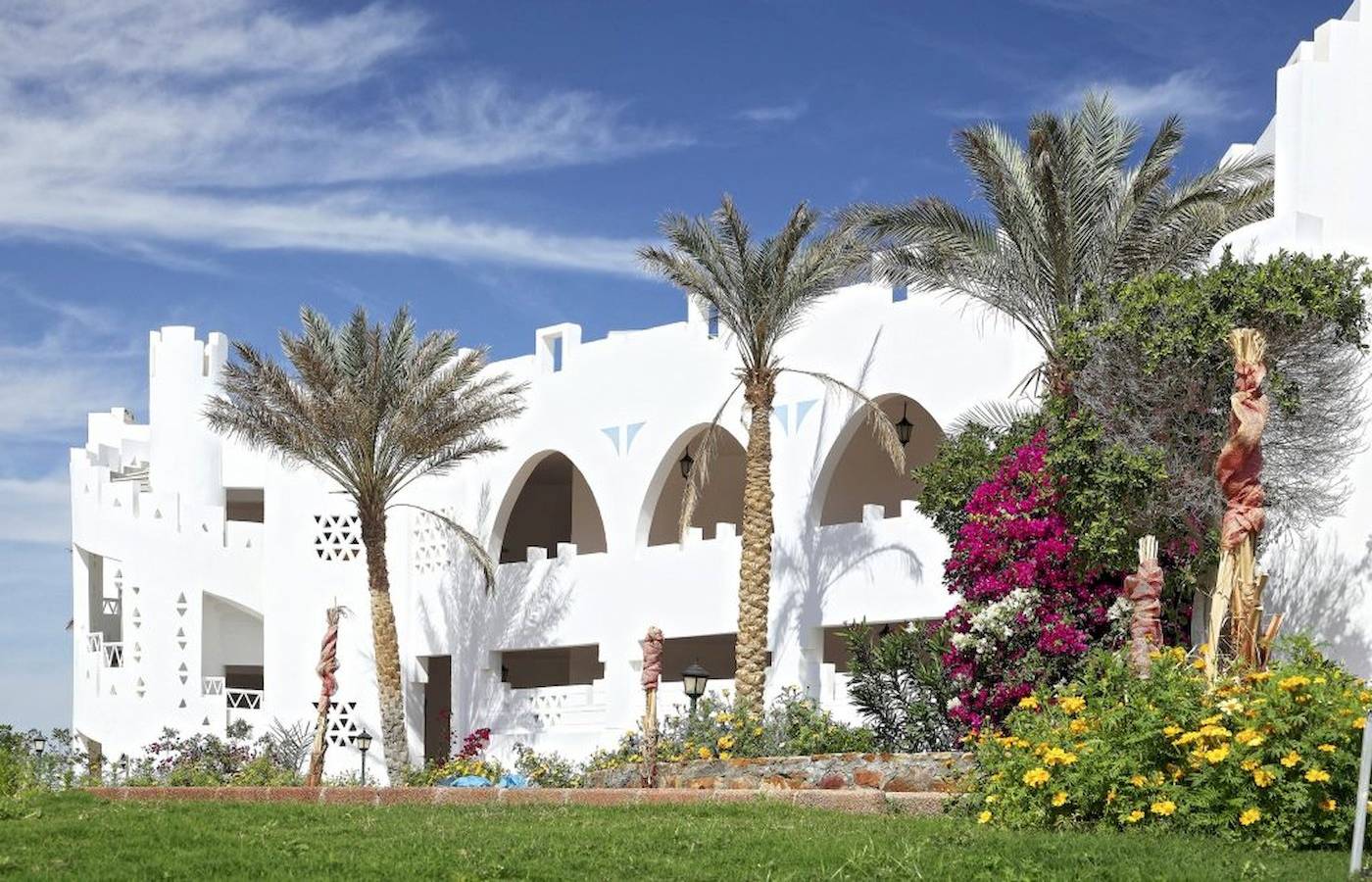 Außenansicht des Three Corners Equinox Beach Resorts mit weißen Gebäuden und Palmen
