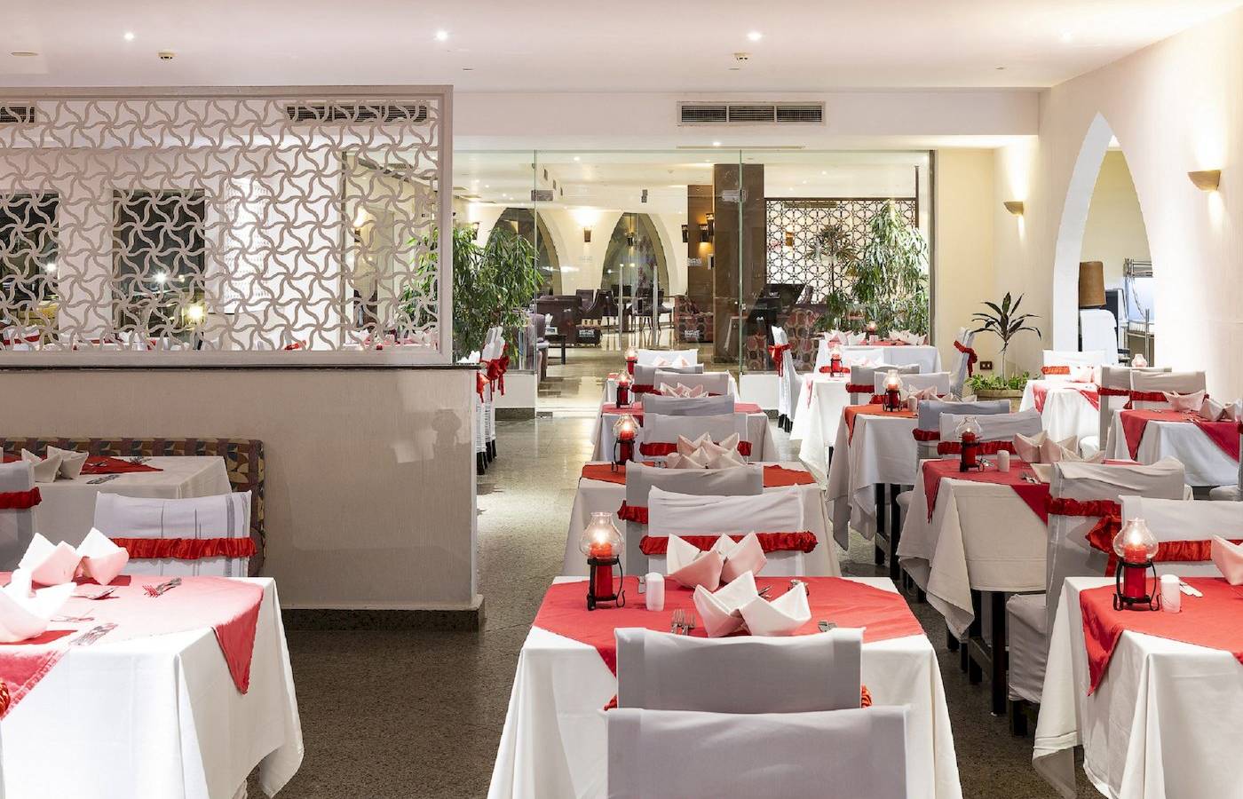 Restaurant-Innenbereich des Three Corners Equinox Beach Resorts mit gedeckten Tischen und roten Tischdecken.
