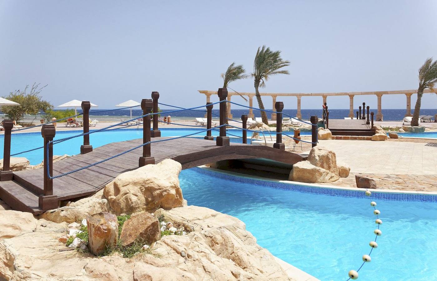 Ein Pool mit einer hölzernen Brücke im Three Corners Equinox Beach Resort