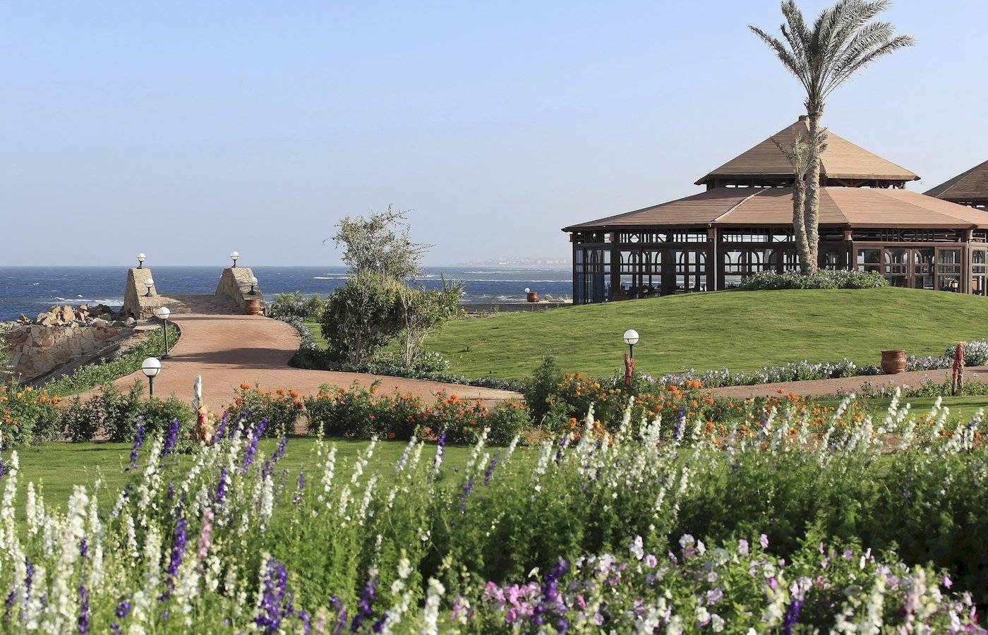 Garten mit Blumen und Gehweg zum Three Corners Equinox Beach Resort.