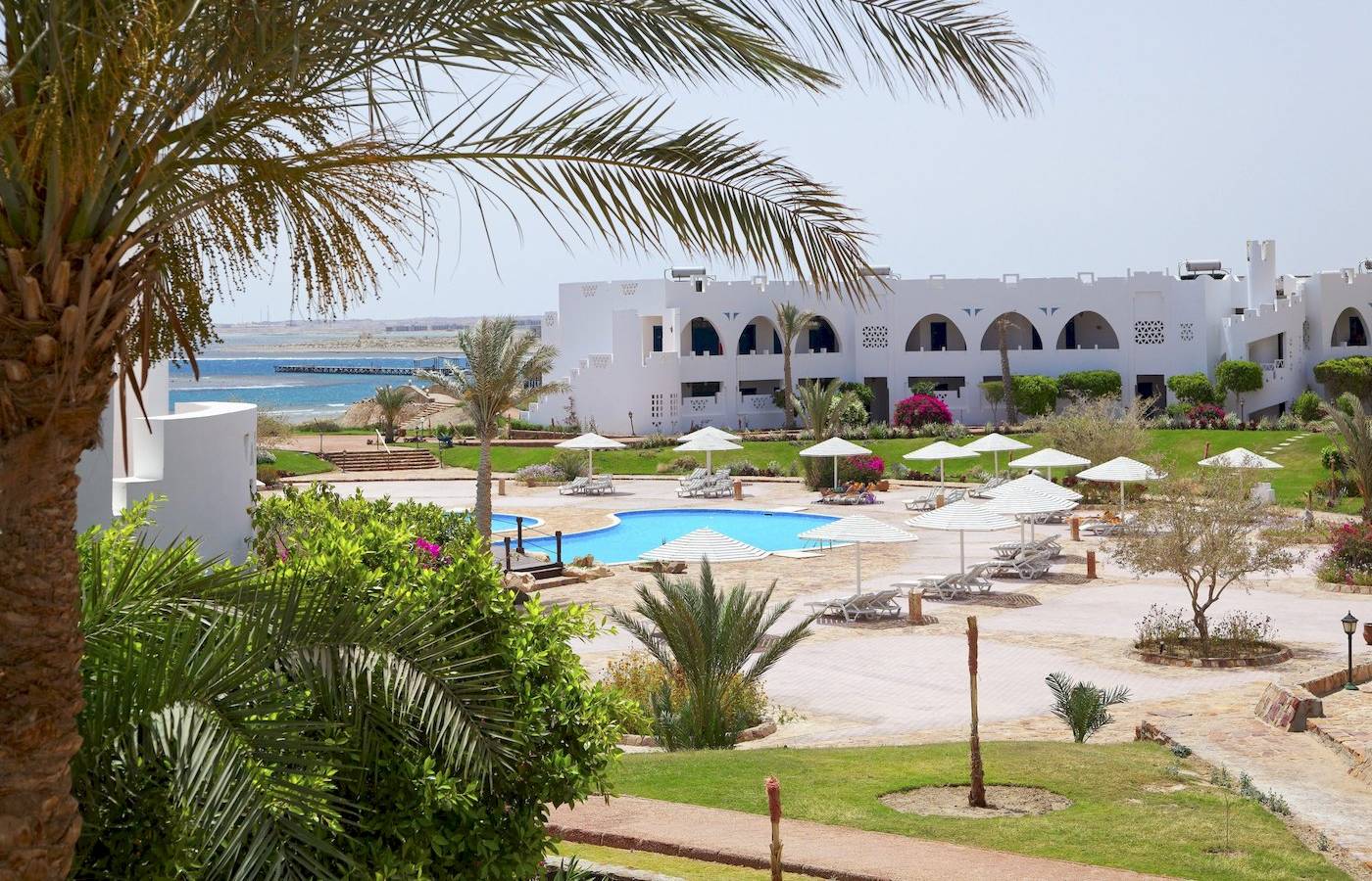 Außenbereich des Three Corners Equinox Beach Resorts mit Pool und Liegen.