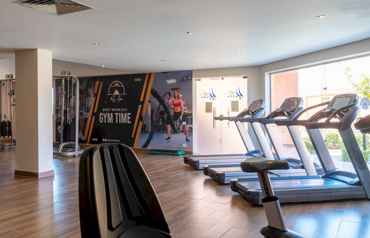 Fitnessstudio im Three Corners Happy Life Beach Resort mit Laufbändern und einer Werbung für Gym Time.
