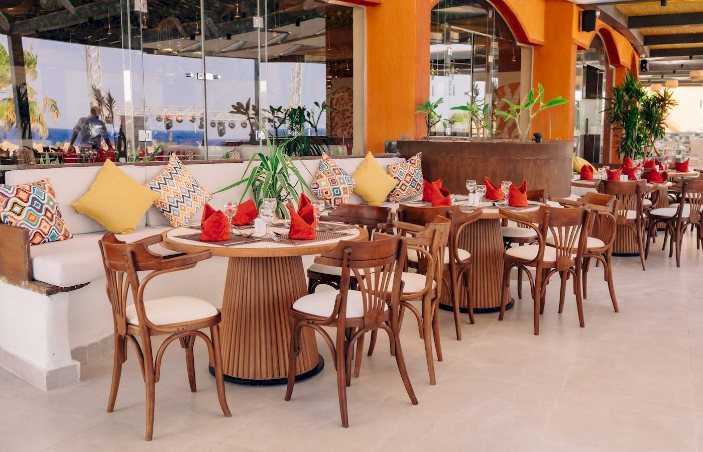 Innenbereich des Restaurants im Three Corners Happy Life Beach Resort mit runden Tischen und Stühlen.