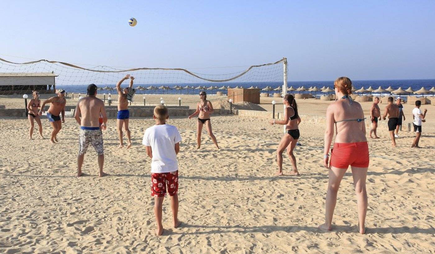 Gruppe von Männern und Frauen spielt Volleyball am Strand des Three Corners Happy Life Beach Resort