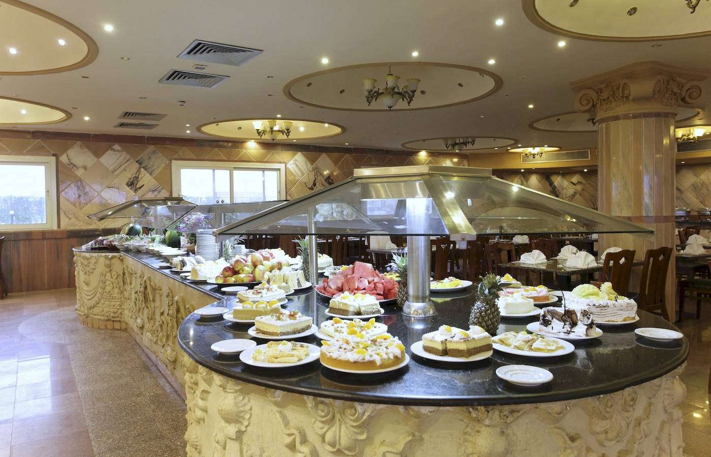 Buffet-Tisch im Three Corners Happy Life Beach Resort mit verschiedenen Kuchen und Obst.