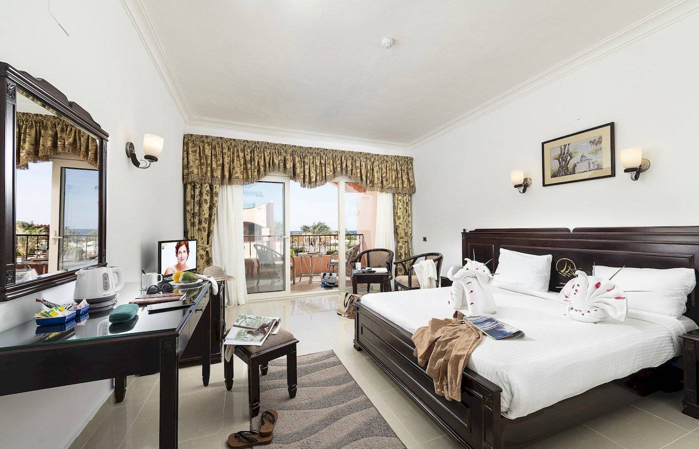 Hotelzimmer des Three Corners Happy Life Beach Resort mit Bett, Fernseher und Balkon.