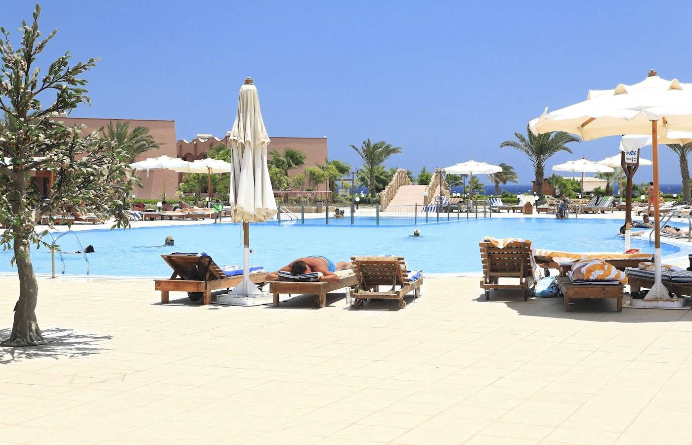 Poolbereich im Three Corners Happy Life Beach Resort mit Sonnenliegen und Sonnenschirmen
