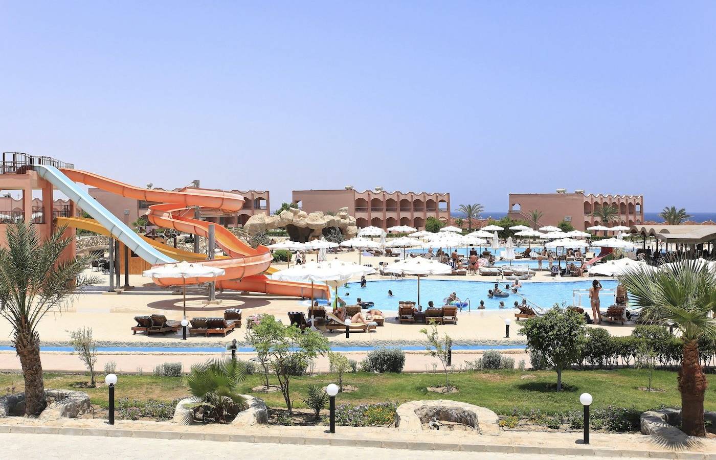 Wasserrutsche im Three Corners Happy Life Beach Resort mit vielen Gästen, die schwimmen und entspannen.