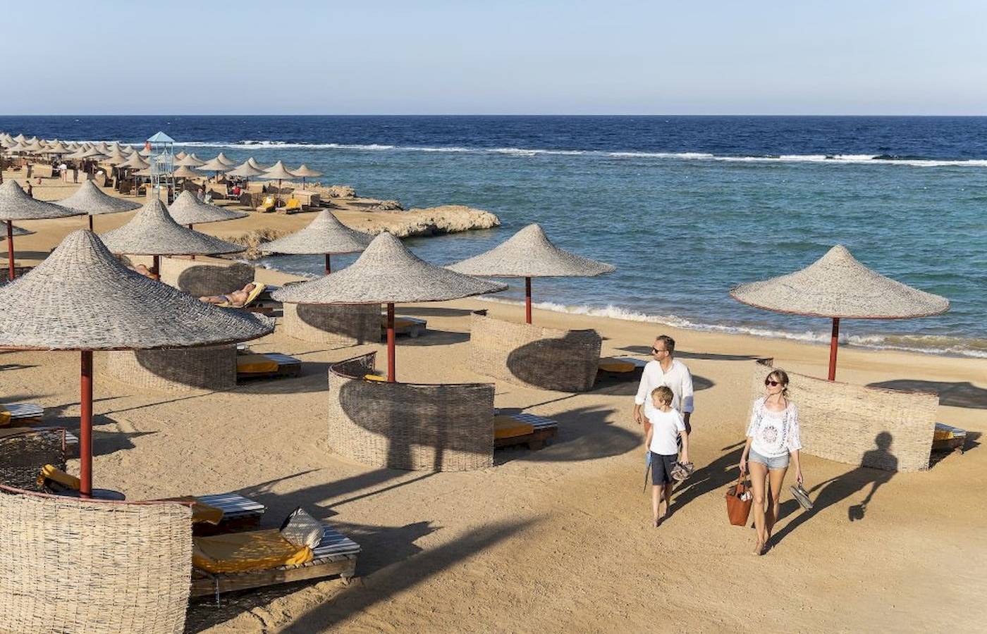 Familie am Strand des Three Corners Happy Life Beach Resorts mit großen Sonnenschirmen