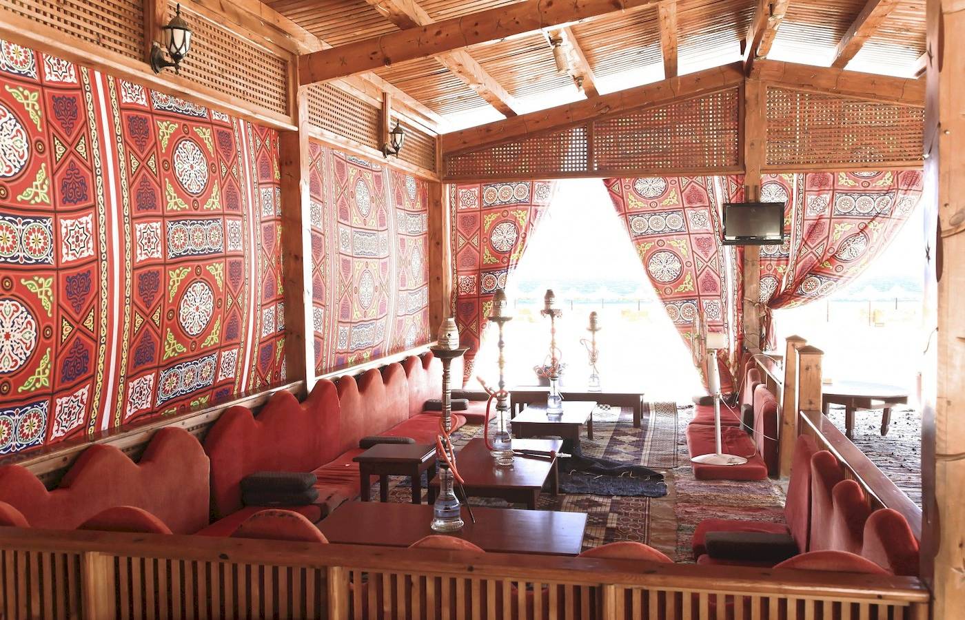 Innenbereich des Three Corners Happy Life Beach Resorts mit roten Sofas, Holztischen und bunten Wandbehängen.