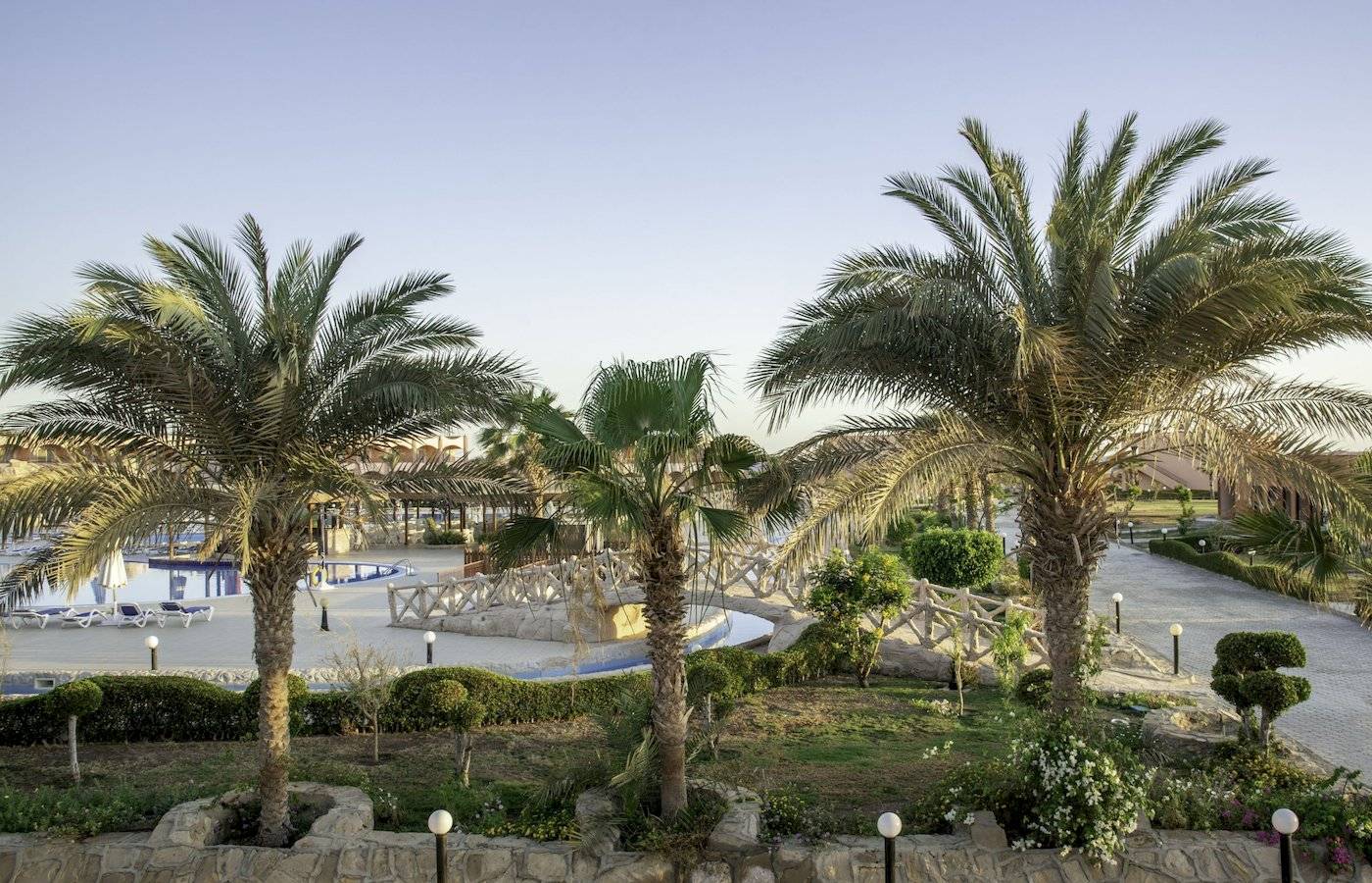 Außenbereich des Three Corners Happy Life Beach Resorts mit Palmen und einem Schwimmbad