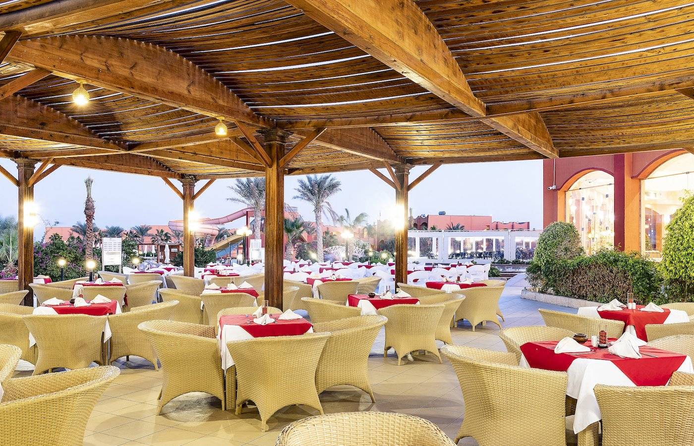 Restaurant im Three Corners Happy Life Beach Resort mit vielen gedeckten Tischen und Stühlen.