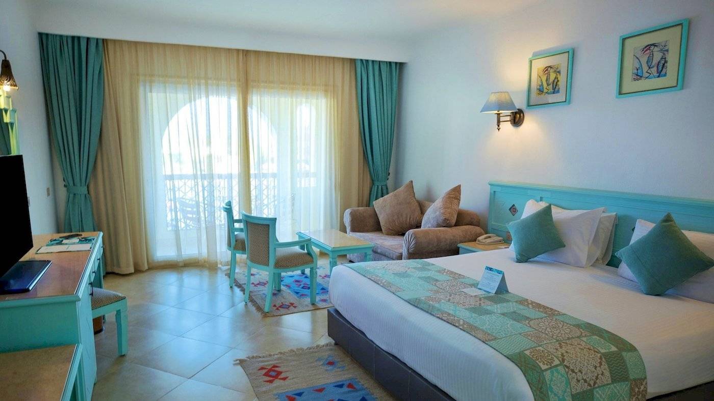 Das elegante Hotelzimmer im Sunrise Royal Makadi Resort mit moderner Einrichtung, großem Bett, Sofa und Schreibtisch.