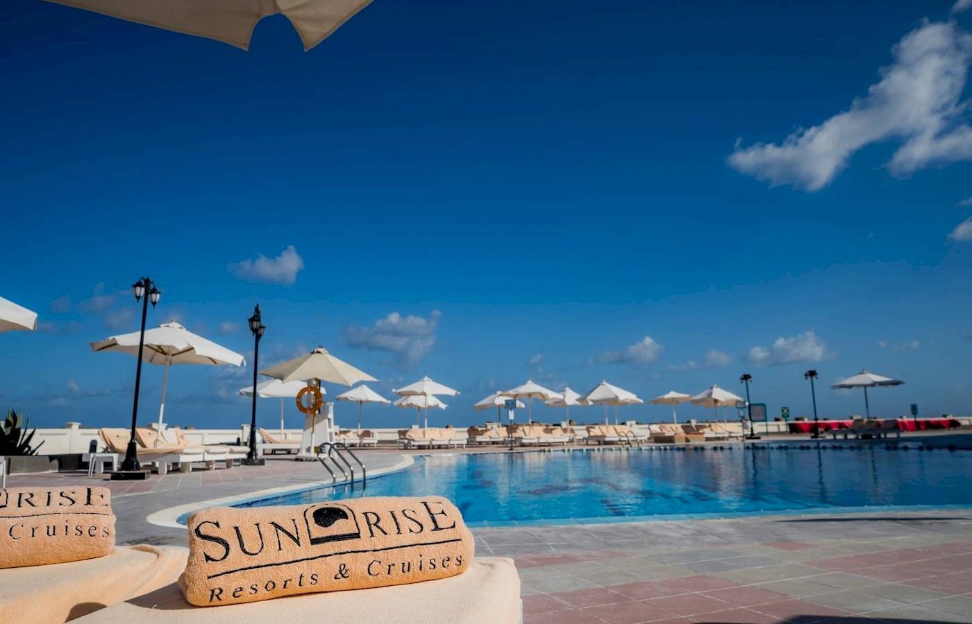 Poolbereich des Sunrise Royal Makadi Resorts mit Liegestühlen und Sonnenschirmen.