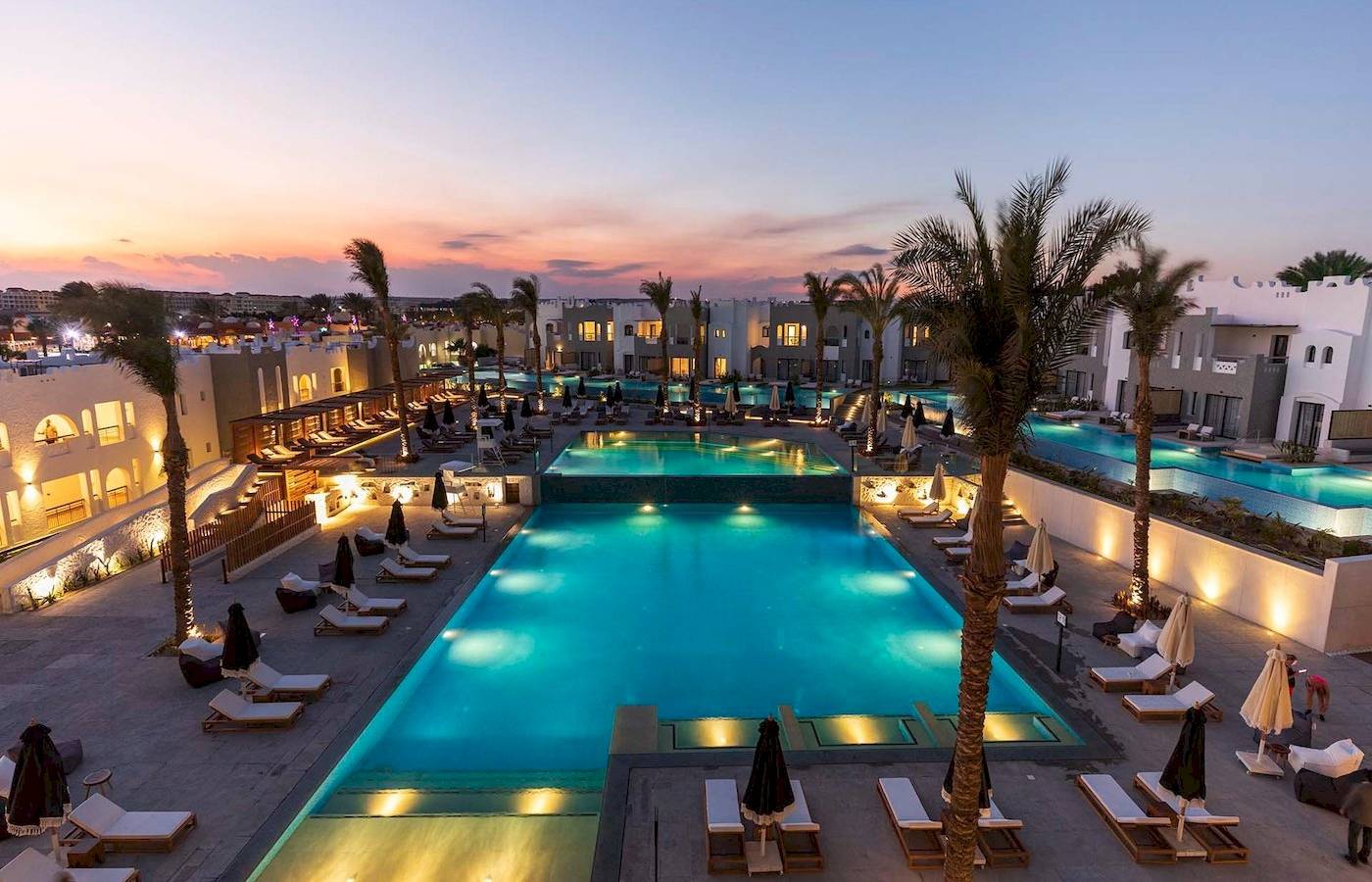 Abendlicher Poolbereich des Sunrise Royal Makadi Resorts mit leuchtenden Palmen und Liegen