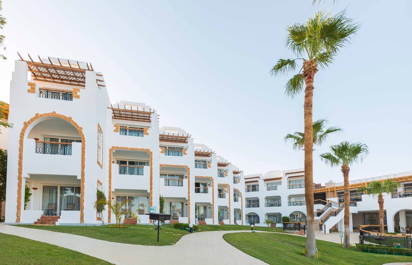 Außenansicht des Sunrise Royal Makadi Resorts mit weißen Gebäuden und Palmen