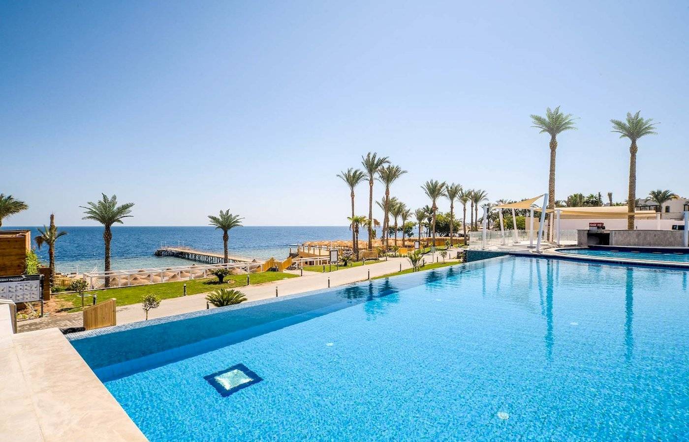 Außenpool am Sunrise Royal Makadi Resort mit Blick auf das Meer und Palmen