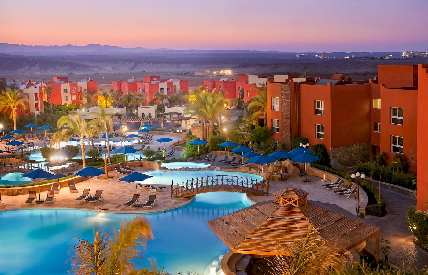 Luftaufnahme des Sunrise Royal Makadi Resorts mit Swimmingpools, Liegestühlen und roten Gebäuden.