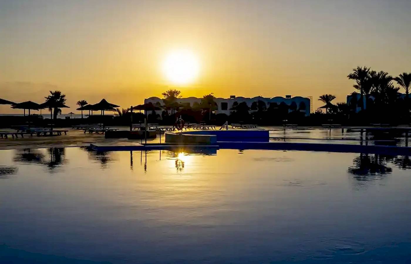 Sonnenuntergang am Gorgonia Beach Resort mit Swimmingpool und Palmen im Hintergrund.