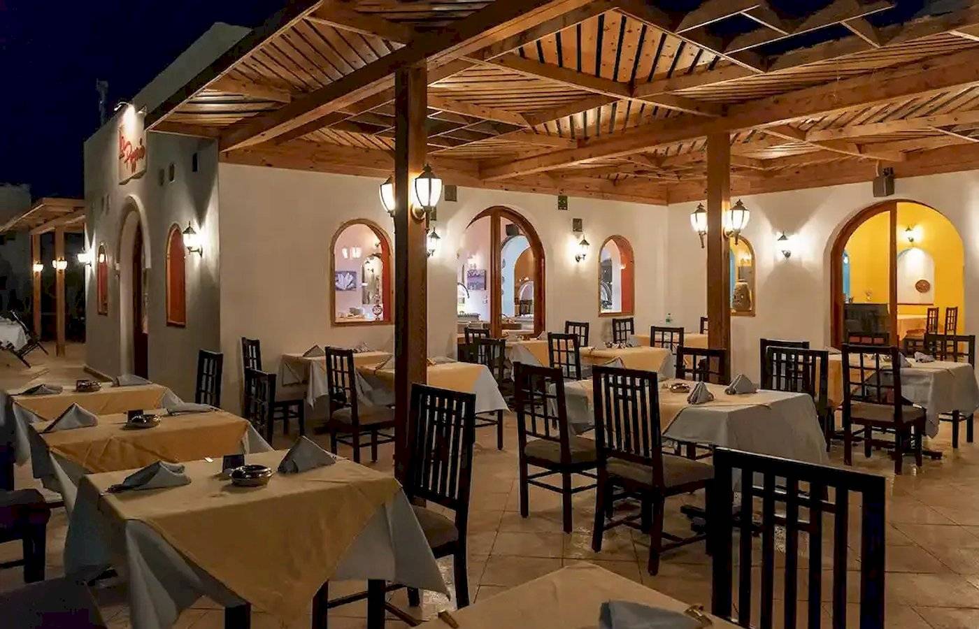 Innenansicht des Restaurants im Gorgonia Beach Resort mit gedeckten Tischen und Holzdecken.
