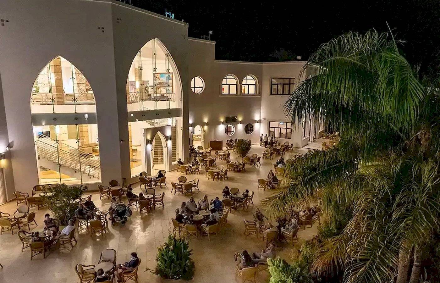 Nachtansicht des Gorgonia Beach Resorts mit vielen Gästen im Außenbereich.
