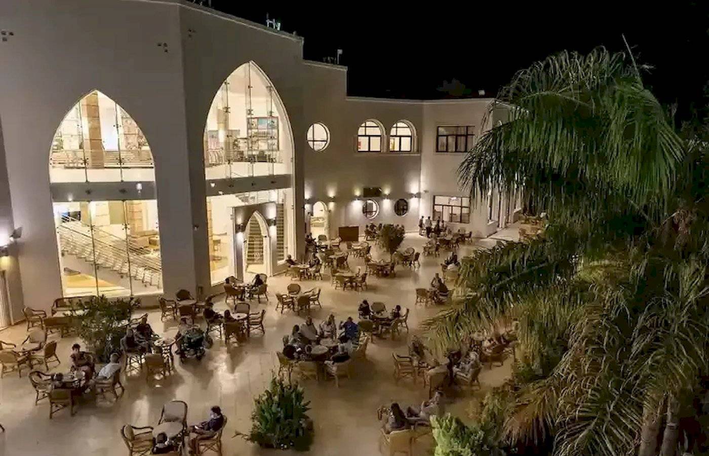 Außenbereich des Gorgonia Beach Resorts bei Nacht mit vielen Gästen an Tischen und Stühlen.