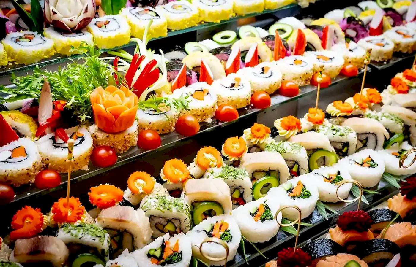 Foto von verschiedenen Sushi-Rollen auf einem Buffet, alle mit verschiedenen Toppings dekoriert.