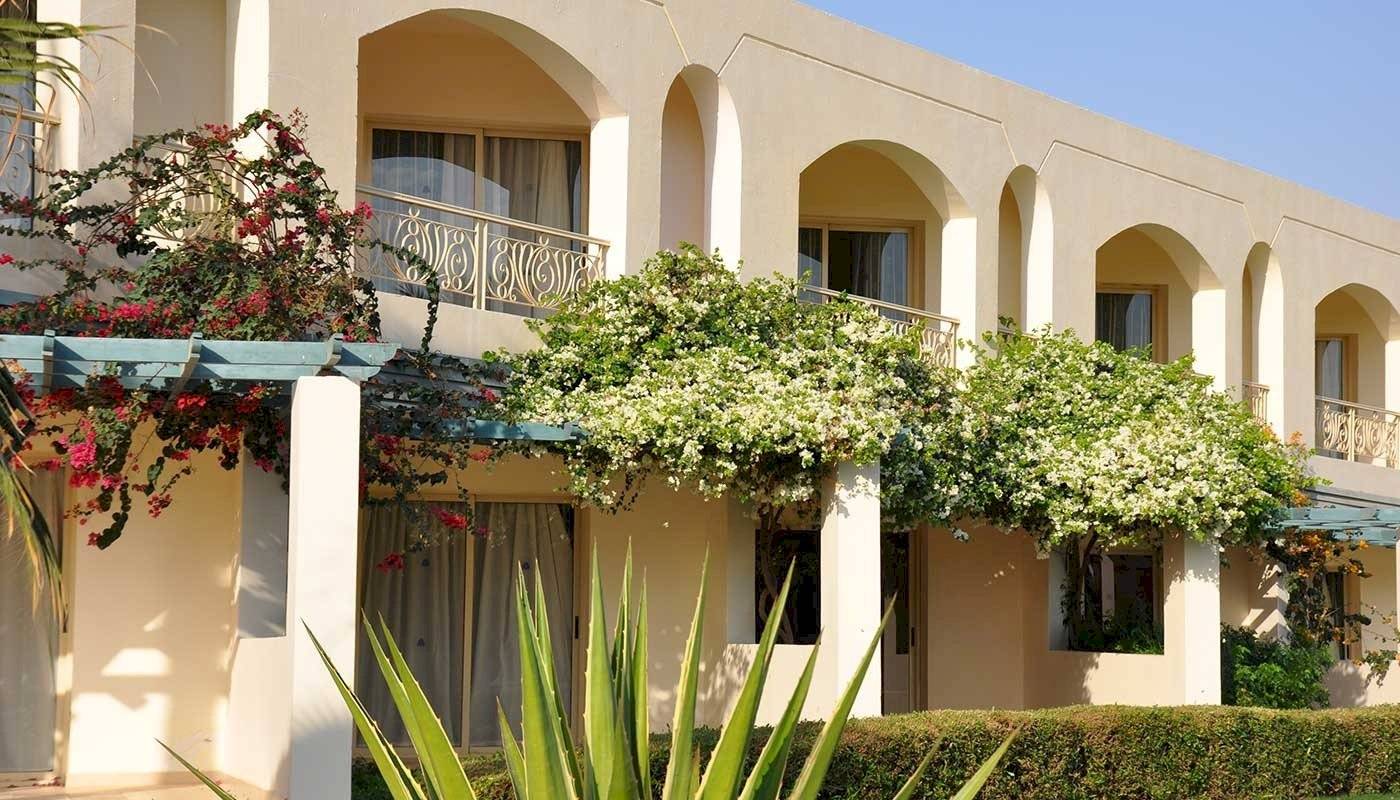 Außenansicht des Brayka Bay Resorts mit blühenden Pflanzen und architektonischen Elementen.